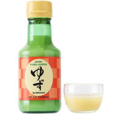Green glass bottle of YUZU JUICE with a yellow cap and red label, accompanied by a small glass cup filled with pale yellow yuzu juice.